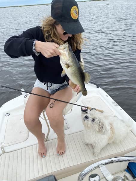 Excited angler with fish and dog on a boat