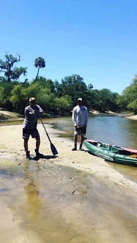 Two men standing next to kayak